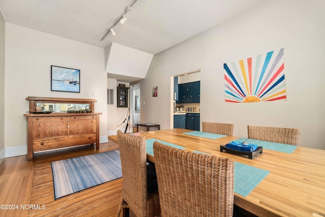 dining space featuring hardwood / wood-style flooring, track lighting, and a textured ceiling