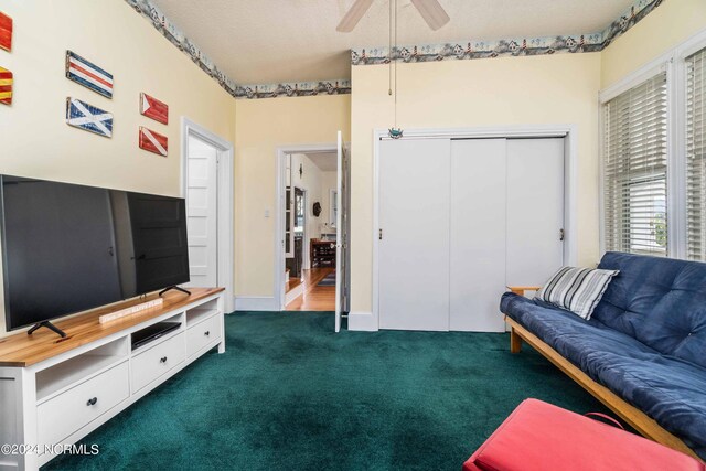 living room featuring a textured ceiling, dark colored carpet, and ceiling fan