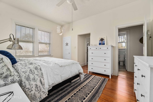 bedroom featuring ceiling fan, a textured ceiling, ensuite bathroom, and dark wood-type flooring