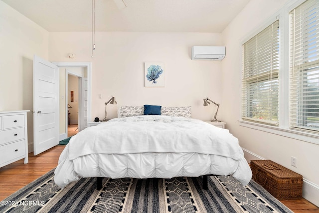 bedroom with light hardwood / wood-style floors, ceiling fan, and a wall mounted air conditioner