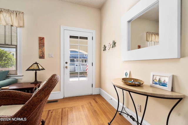 doorway to outside with light wood-type flooring and a textured ceiling