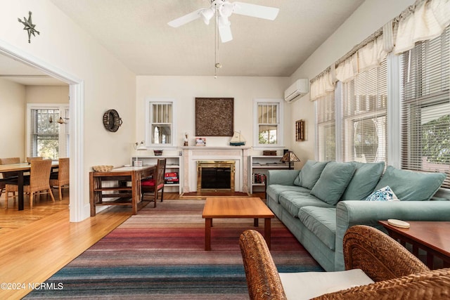 living room featuring ceiling fan, wood-type flooring, and a wall unit AC