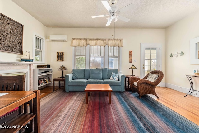 living room featuring ceiling fan, a textured ceiling, a healthy amount of sunlight, and a wall mounted AC