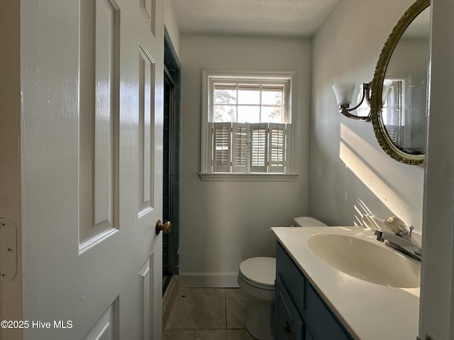 bathroom with a textured ceiling, toilet, vanity, and tile patterned flooring