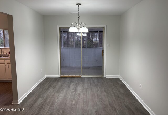 spare room featuring dark colored carpet, a chandelier, and a textured ceiling