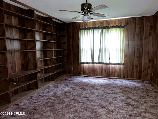 spare room featuring a textured ceiling, plenty of natural light, wood walls, and ceiling fan