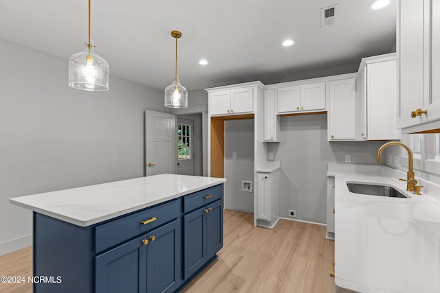 kitchen featuring light stone countertops, blue cabinetry, sink, white cabinetry, and decorative light fixtures