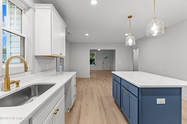 kitchen with a healthy amount of sunlight, blue cabinetry, sink, and white cabinets