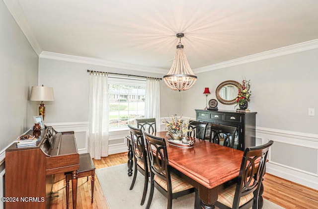 dining room with ornamental molding, light wood-type flooring, and a notable chandelier