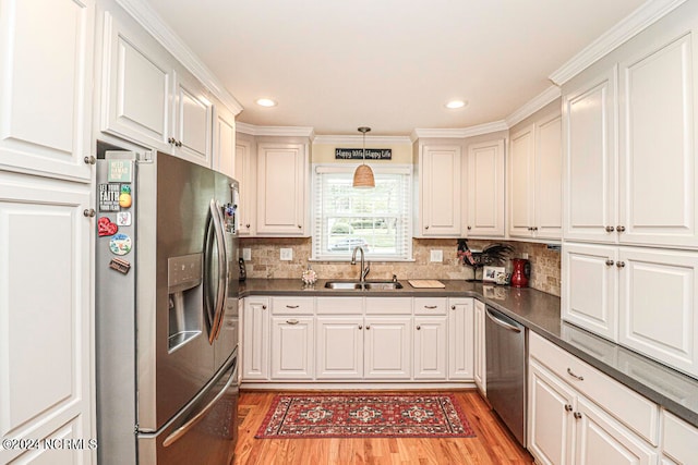 kitchen with white cabinets, sink, stainless steel appliances, crown molding, and light hardwood / wood-style floors