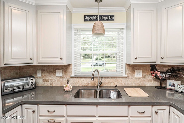 kitchen featuring hanging light fixtures, decorative backsplash, sink, and white cabinets