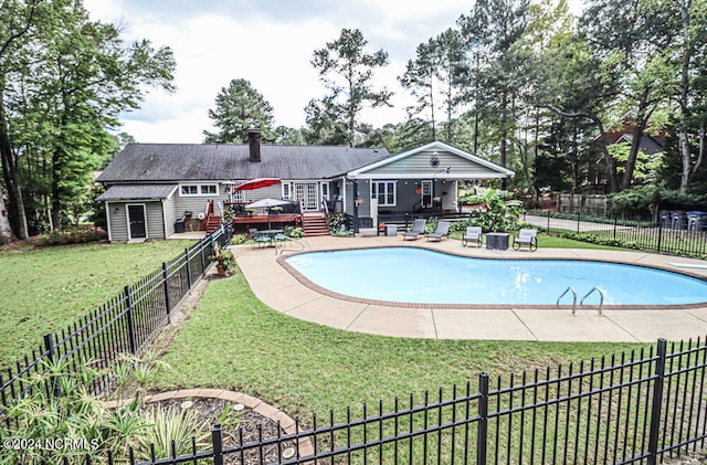 view of pool with a wooden deck, a lawn, a patio, and an outbuilding