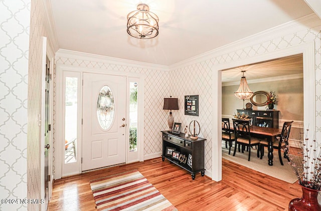 foyer entrance with crown molding, light hardwood / wood-style floors, and a chandelier