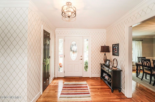 entrance foyer with ornamental molding, wood-type flooring, and a notable chandelier