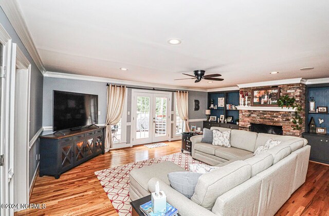 living room featuring hardwood / wood-style flooring, a fireplace, crown molding, ceiling fan, and french doors