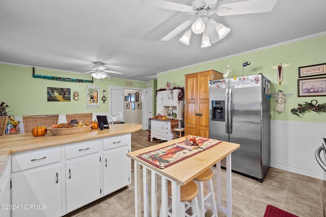 kitchen with ceiling fan, white cabinets, stainless steel refrigerator with ice dispenser, and crown molding