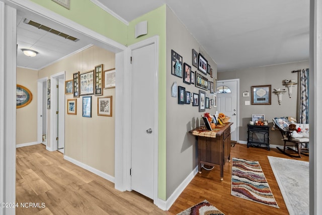 hallway with crown molding and light hardwood / wood-style floors