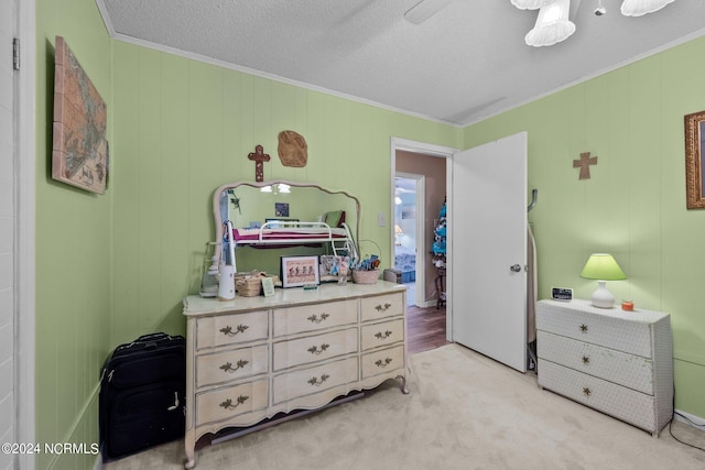 carpeted bedroom featuring ornamental molding, ceiling fan, and a textured ceiling