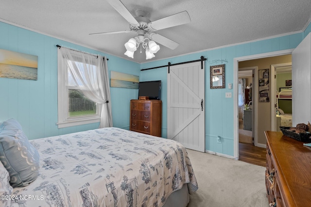 bedroom with a barn door, a textured ceiling, light carpet, and ceiling fan