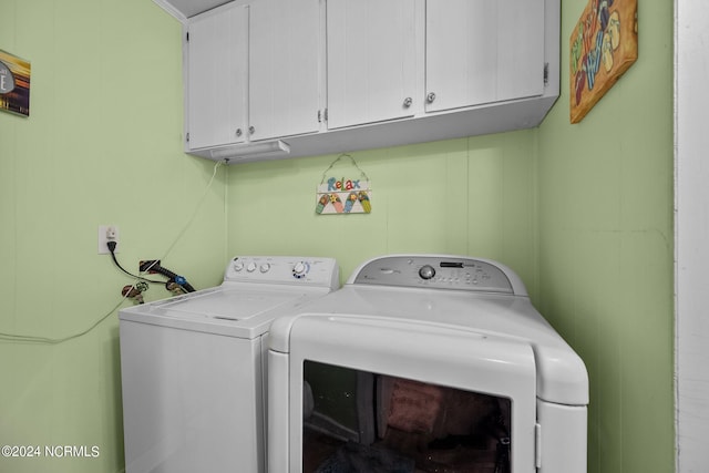 laundry area with washing machine and clothes dryer and cabinets