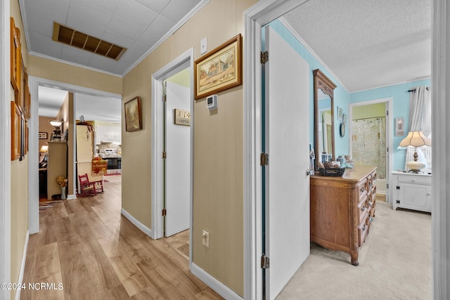 hall featuring a textured ceiling, ornamental molding, and light hardwood / wood-style flooring