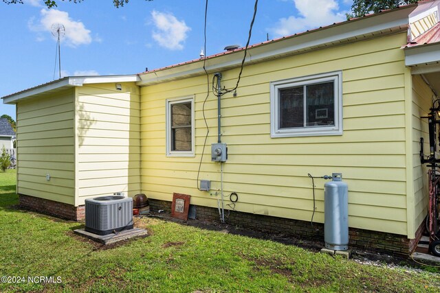 view of property exterior with a lawn and cooling unit