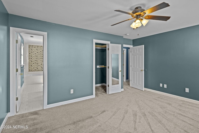 unfurnished bedroom with light carpet, ceiling fan, a walk in closet, and ensuite bathroom