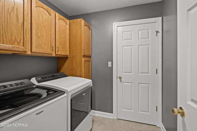 clothes washing area featuring cabinets, washing machine and clothes dryer, and light tile patterned flooring