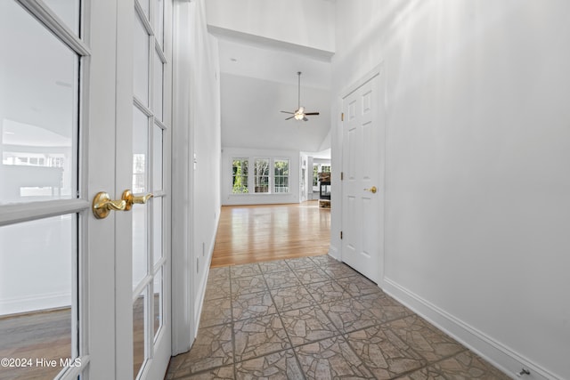 hallway featuring light wood-type flooring and high vaulted ceiling