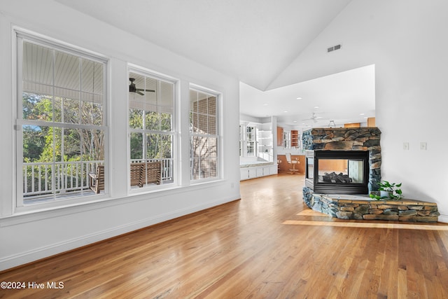 living room featuring ceiling fan, light hardwood / wood-style floors, a fireplace, and high vaulted ceiling