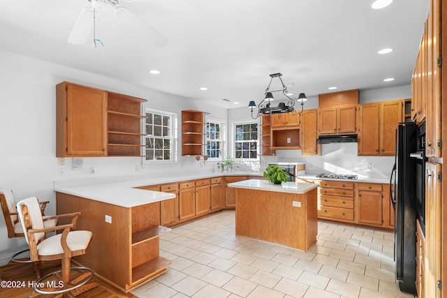 kitchen featuring kitchen peninsula, ceiling fan with notable chandelier, decorative light fixtures, a center island, and stainless steel gas stovetop