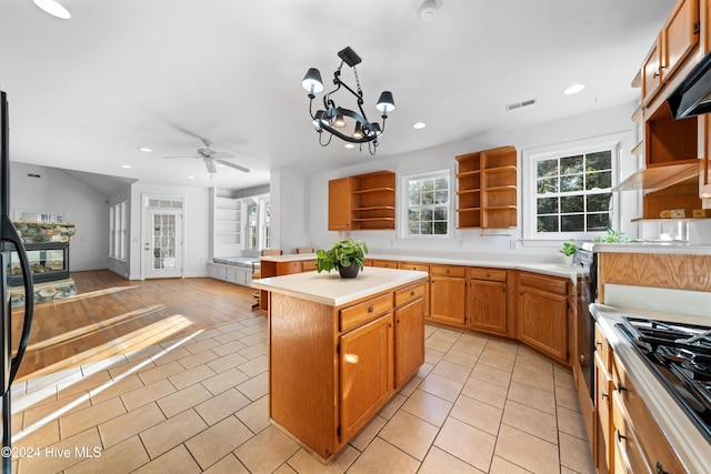 kitchen with a center island, ceiling fan with notable chandelier, hanging light fixtures, light hardwood / wood-style floors, and stainless steel gas cooktop