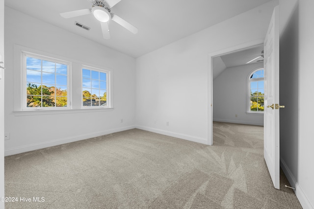 carpeted empty room featuring ceiling fan, a healthy amount of sunlight, and lofted ceiling