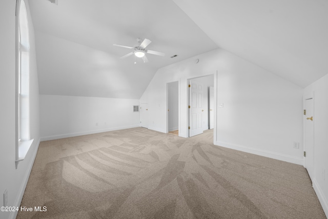 additional living space with light colored carpet, vaulted ceiling, and ceiling fan