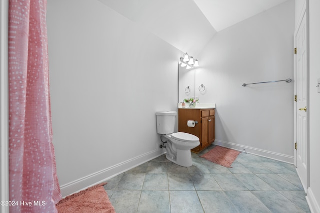 bathroom with tile patterned flooring, vanity, toilet, and vaulted ceiling