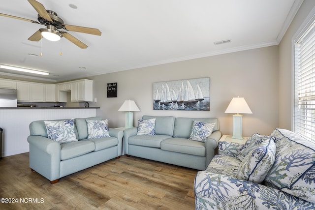 living room featuring ceiling fan, ornamental molding, and light wood-type flooring