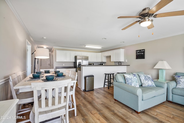 living room featuring crown molding, ceiling fan, and light wood-type flooring