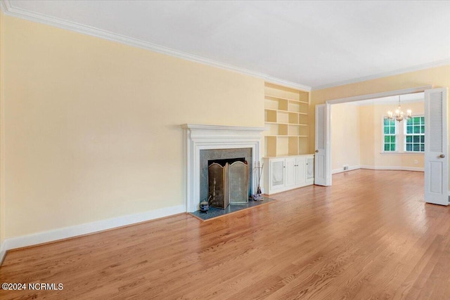 unfurnished living room with an inviting chandelier, ornamental molding, hardwood / wood-style floors, and built in features