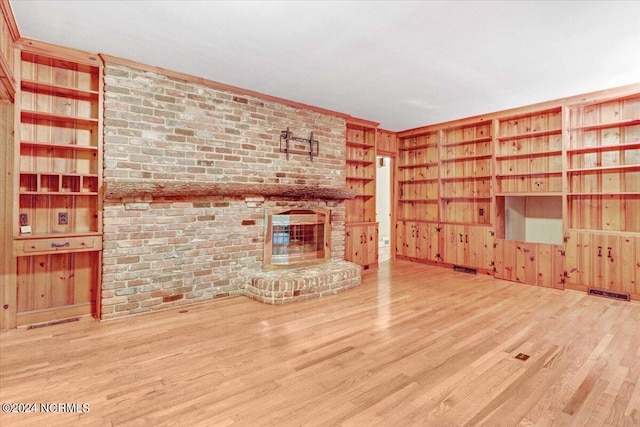 unfurnished living room with a brick fireplace, wood walls, and wood-type flooring