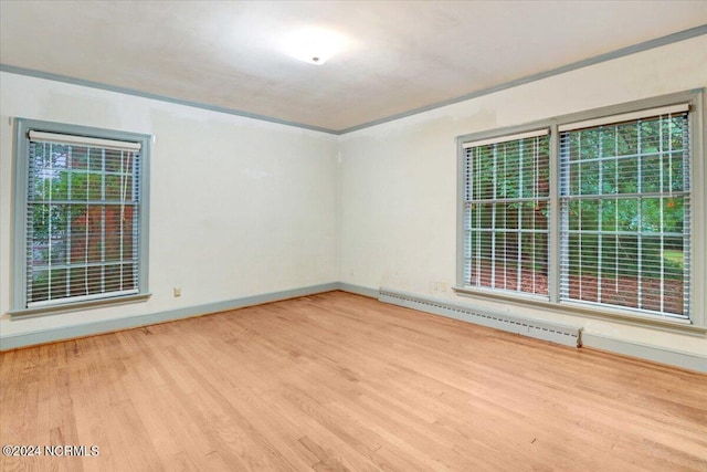 unfurnished room with crown molding, light hardwood / wood-style floors, a baseboard heating unit, and a wealth of natural light