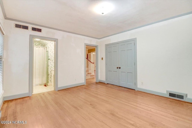 unfurnished bedroom featuring light wood-type flooring, a closet, and ensuite bathroom