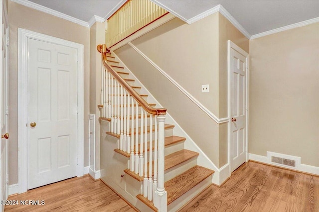 stairs featuring ornamental molding and hardwood / wood-style floors