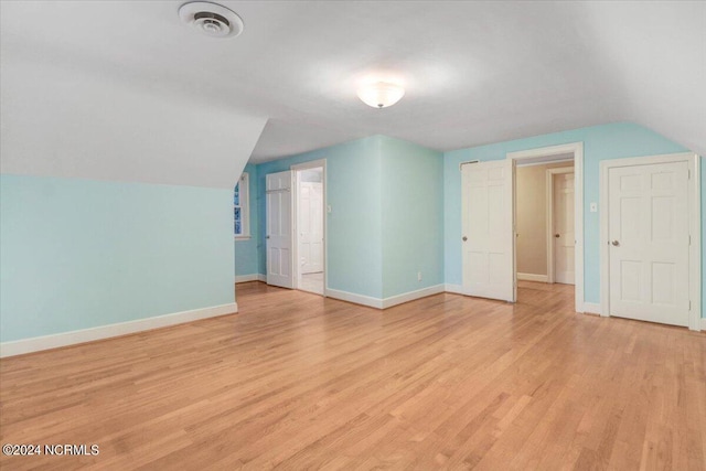 additional living space with light hardwood / wood-style flooring and lofted ceiling