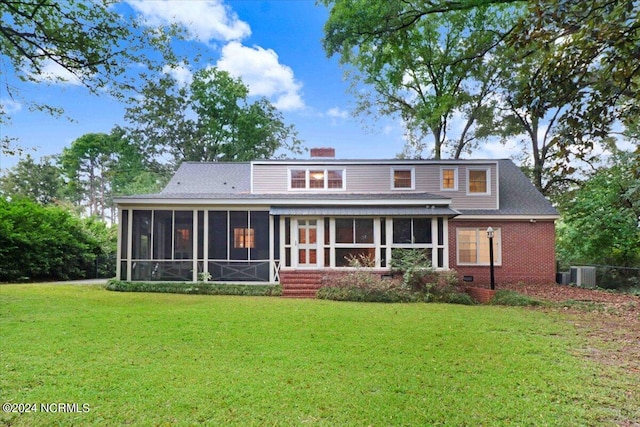 back of property featuring a lawn, a sunroom, and central AC unit