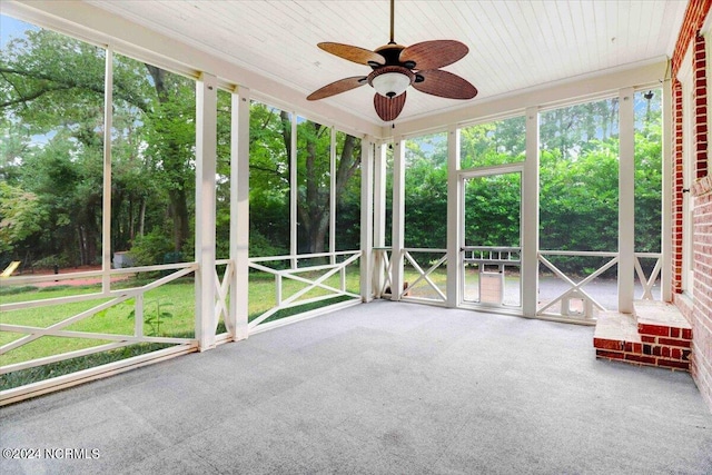 unfurnished sunroom featuring wood ceiling and ceiling fan