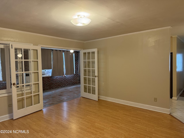 empty room featuring ornamental molding, light wood-type flooring, brick wall, and french doors