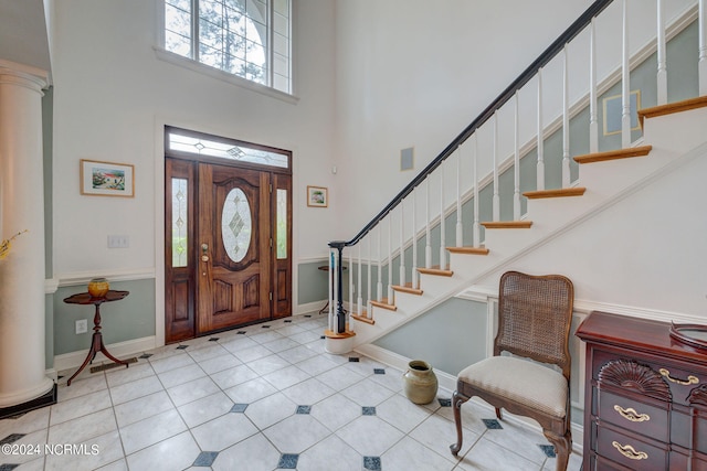 foyer entrance featuring a towering ceiling and ornate columns