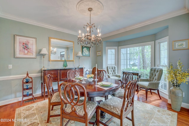 dining space with an inviting chandelier, light wood-type flooring, and crown molding