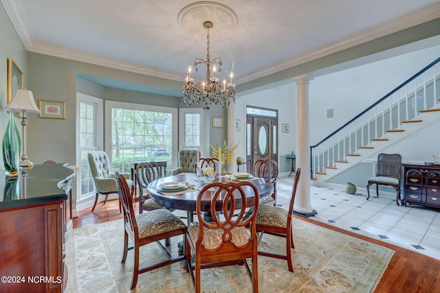 dining space featuring ornamental molding, light hardwood / wood-style flooring, a chandelier, and ornate columns