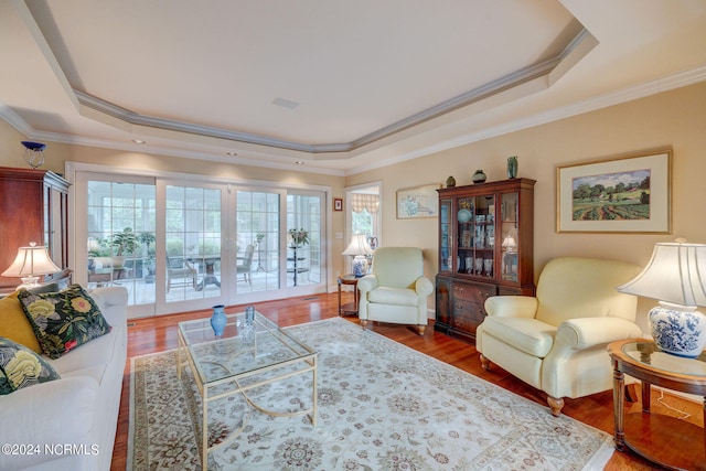 living room with ornamental molding, a tray ceiling, and hardwood / wood-style flooring